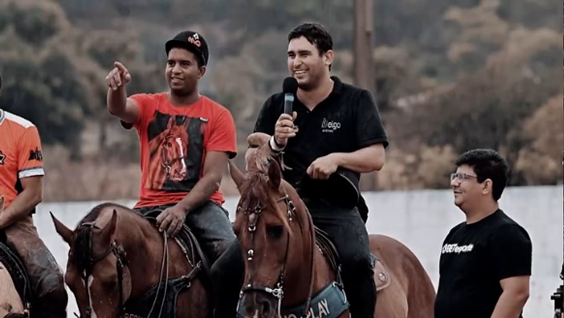 Cavaleiros em evento da região, um deles com microfone na mão
